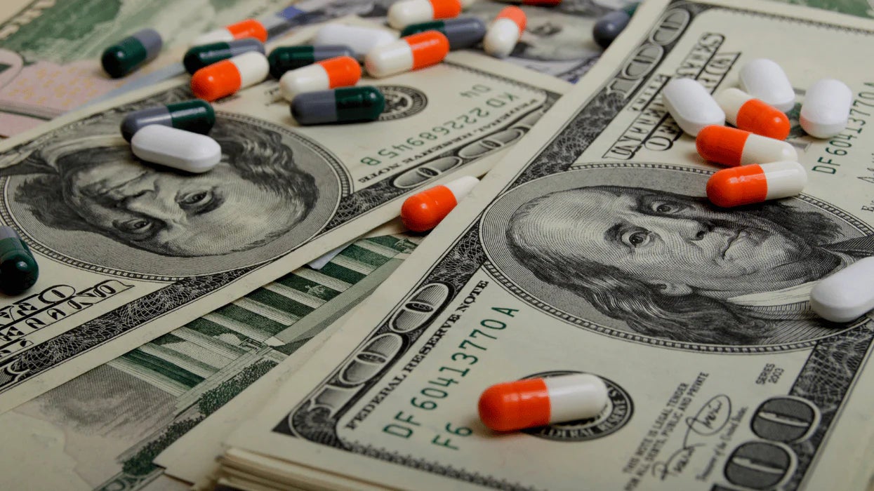 Pillole e capsule sparse su banconote da cento dollari